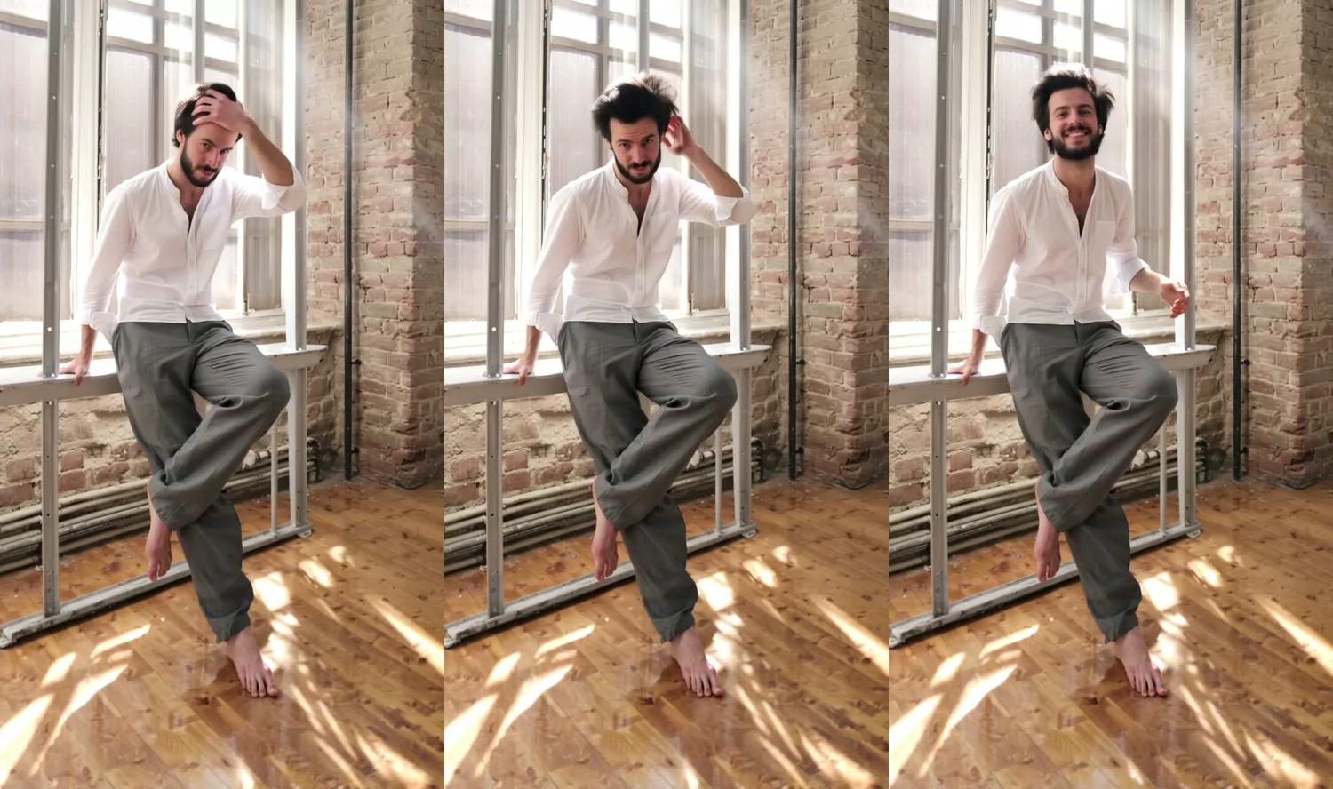 Tre fotogrammi verticali di un uomo adulto con una barba corta e capelli scuri scompigliati in camicia di lino bianca e pantaloni grigi, scalzo in un loft di mattoni illuminato dal sole, appoggiato a una ringhiera di acciaio, che si passa una mano tra i capelli e poi sorride alla camera.