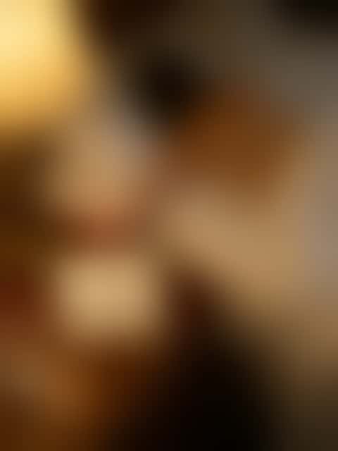 A handwritten card reading WAKE ME BEFORE YOU GO propped against a bedside lamp, a sleeping woman blurred behind it.