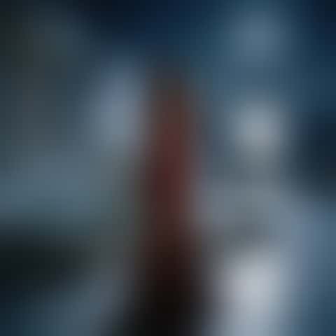 On a moonlit marble palace terrace with a fountain and the sea behind, the camera circles a woman in a red backless satin gown from front to side to back as she glances over her shoulder