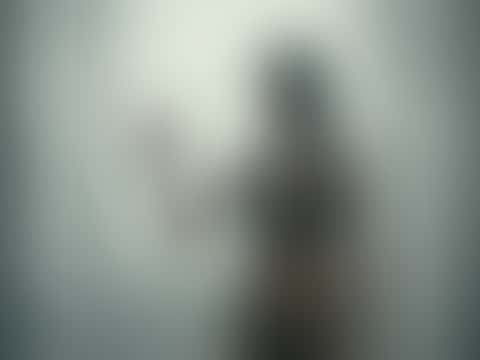 Behind fogged glass, a woman drags her palm down the steamed pane, backlit by a bright window as steam rolls across the frame