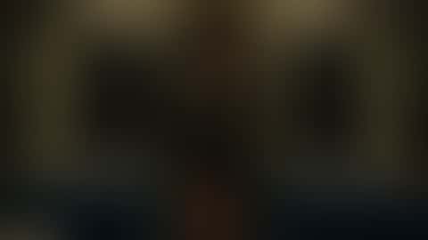 In a dim night train carriage, a woman in a long dark coat with bare legs stands at the door; a man steps in behind her and they end up face to face as tunnel lights strobe