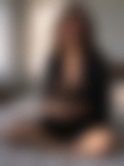 The same woman, face, hairstyle, pose, cup and bed unchanged, now in a black silk wrap, with the morning light turned into slanting afternoon sun.