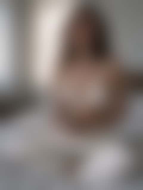 A woman in loose linen trousers sits cross-legged holding a ceramic cup, soft morning light coming through the curtains.