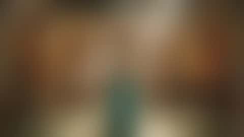 In una sala di palazzo piena di lanterne e circondata da musicisti seduti, una danzatrice del ventre con top turchese ingioiellato e ampia gonna turchese gira con la gonna aperta e finisce sorridendo in camera