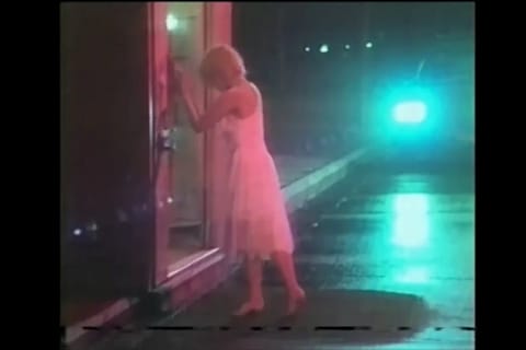 Kobieta w drzwiach nocą z liniami śledzenia VHS, z LoRA w stylu kasety VHS na MiniMax H3