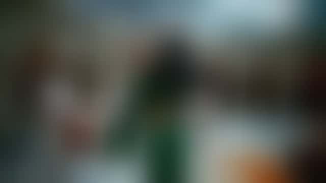 Nel cortile bagnato di un palazzo indiano, tra petali di calendula che cadono e suonatori di dhol in bianco, una donna in sari verde smeraldo e blusa corta gira con le braccia alzate e si volta sorridendo verso la camera