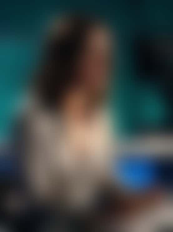 Una conduttrice del telegiornale in camicetta di seta parla alla scrivania dello studio; l’inquadratura si stringe finché restano solo il collo e il colletto aperto