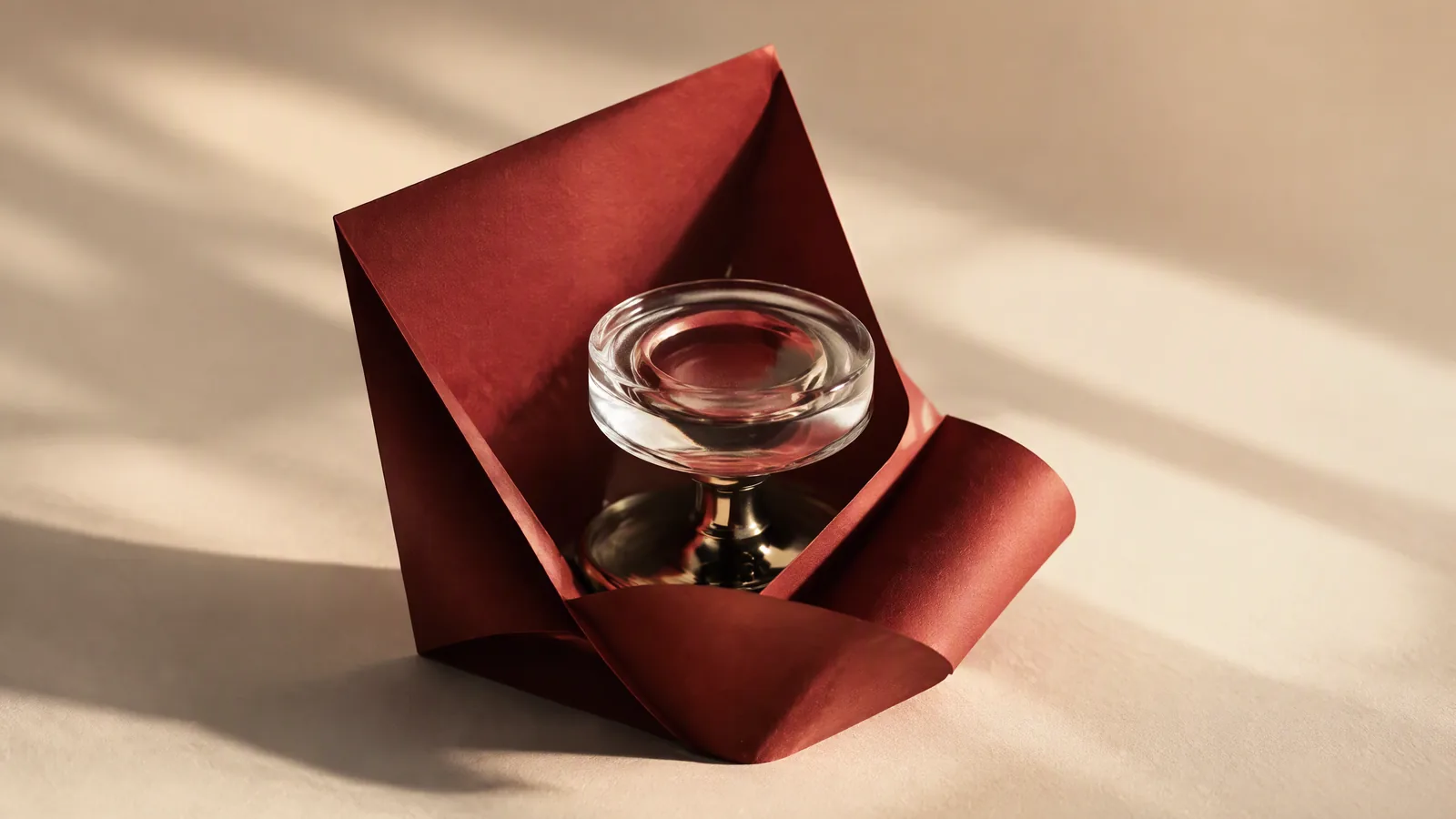 A glass ornament beside folded crimson paper